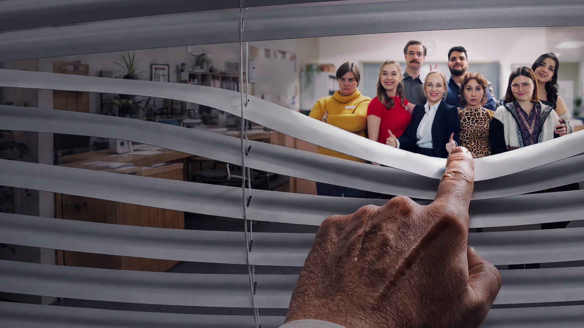 "Nine to Five – Das Amt": Eine Hand biegt eine Jalousie herunter und blickt auf eine Gruppe von sieben lächelnden Büroangestellten. Das diverse Team posiert gemeinsam in einem hellen Großraumbüro.