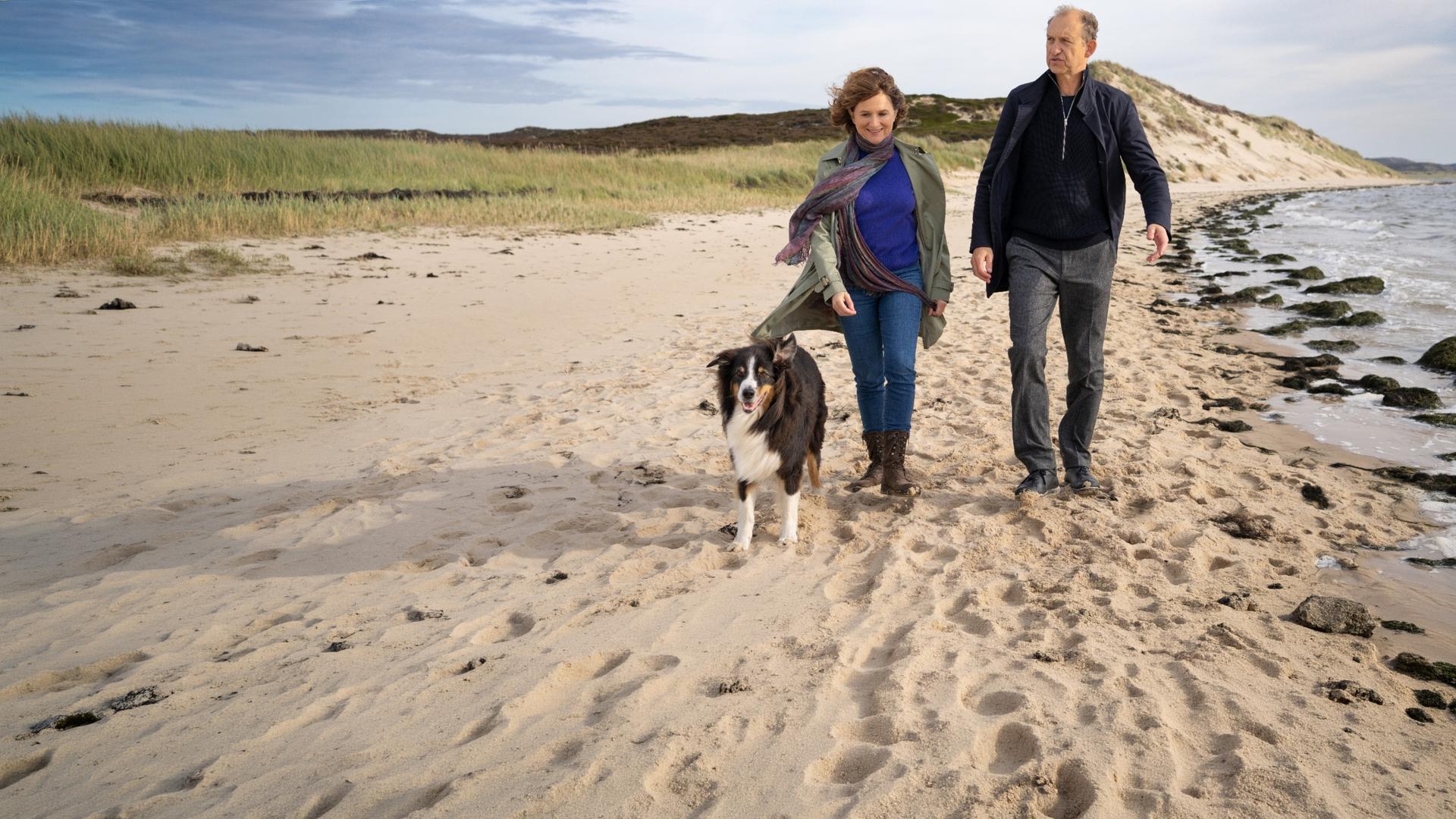 Tabea Krawinkel (Victoria Trauttmansdorff) und Carl Sievers (Peter Heinrich Brix) laufen nebeneinander am Strand entlang. Neben ihnen läuft der Hund Joker.