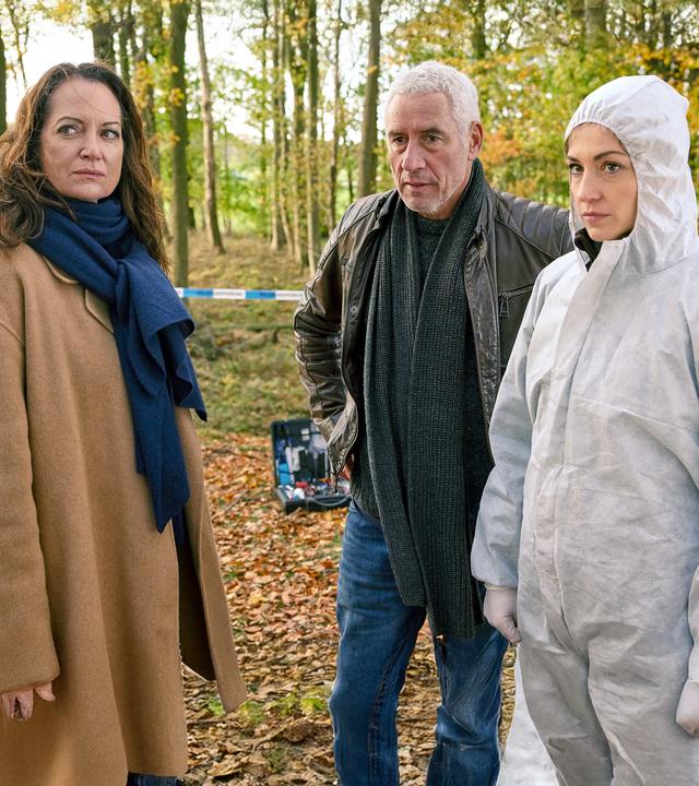 Jana Winter (Natalia Wörner), Matthias Hamm (Ralph Herforth) und Rechtsmedizinerin (Sophia Schubert) stehen an einem Tatort im Wald.