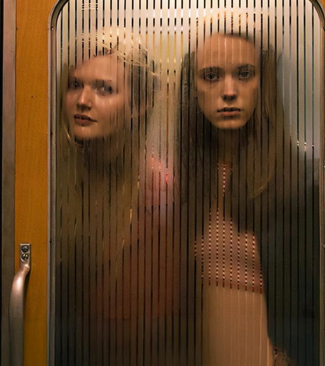 Joe (Stacy Martin, r.) und Schulfreundin B (Sophie Kennedy Clark) blicken durch die Glastür eines Zuges in die 1. Klasse.