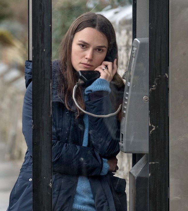 Katharine Gun (Keira Knightley) steht in einer halboffenen öffentlichen Telefonzelle und telefoniert.