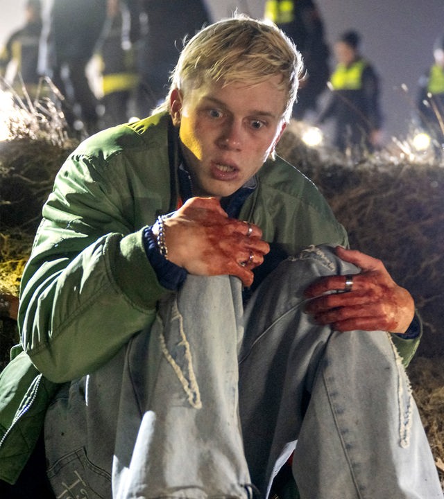 Sichtlich verängstigt und traumatisiert sitzt Marvin Claudius (Noah Kraus) draußen auf dem Boden an einer Düne. Seine Hände sind blutig, er umschlingt seine Knie. Im Hintergrund sieht man verschwommenen mehrere Polizisten (Komparsen) mit Taschenlampen.