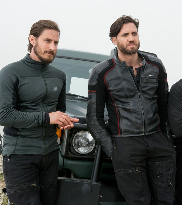 Roach (Clemens Schick), Bodhi (Édgar Ramírez) und Grommet (Matias Varela) stehen nebeneinander vor einem Jeep und blicken herausfordernd auf ihr Gegenüber.