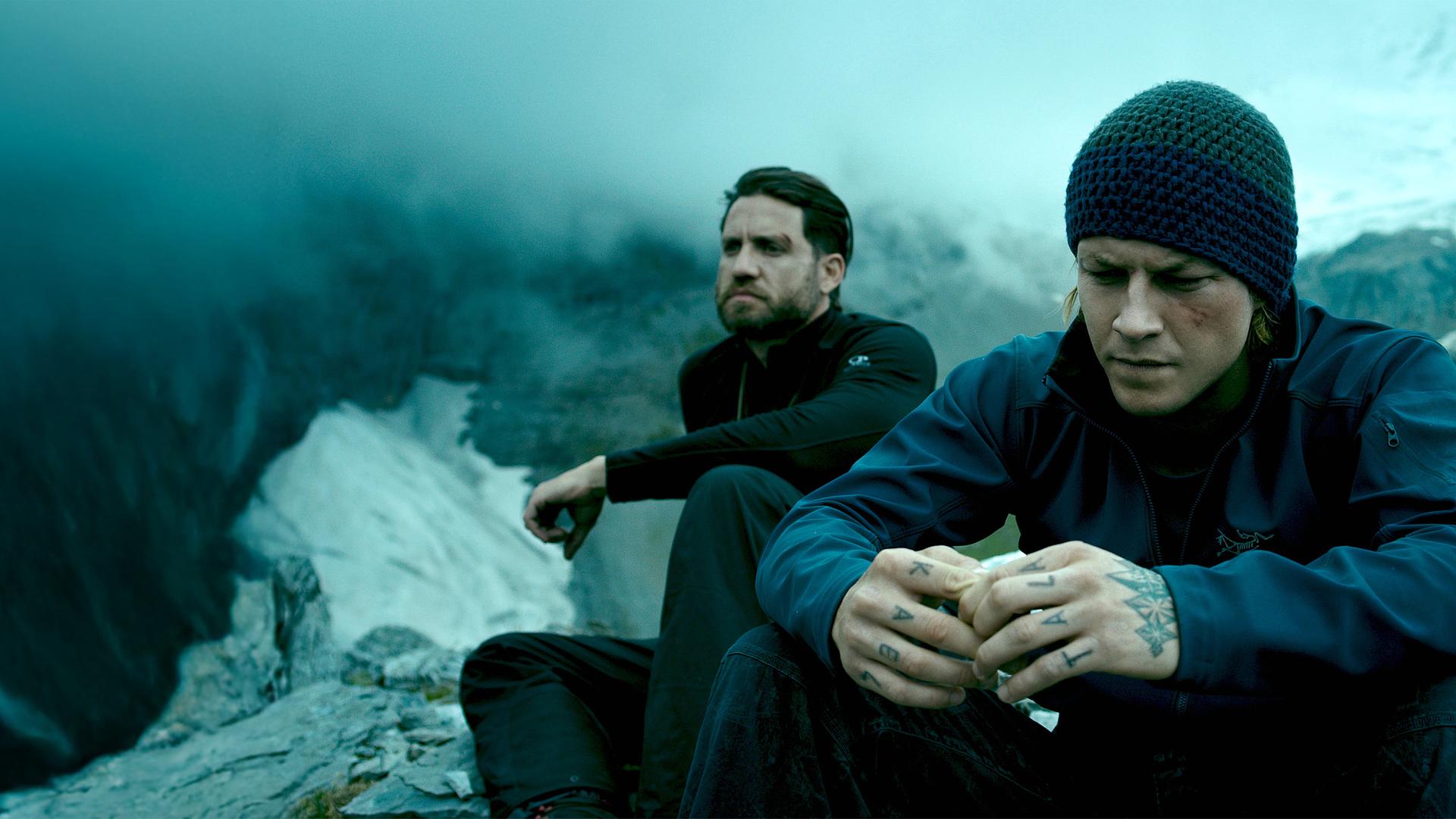 "Point Break": Johnny Utah (Luke Bracey) und Bodhi (Édgar Ramírez, l.) sitzen nebeneinander auf einem Berggipfel und blicken konzentriert vor sich hin.