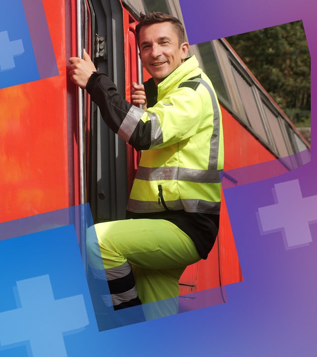 Eric Mayer erklimmt in einer gelben Arbeitsmontur die Leiter zum Führerstand einer roten Lokomotive. Dabei lächelt er in die Kamera.