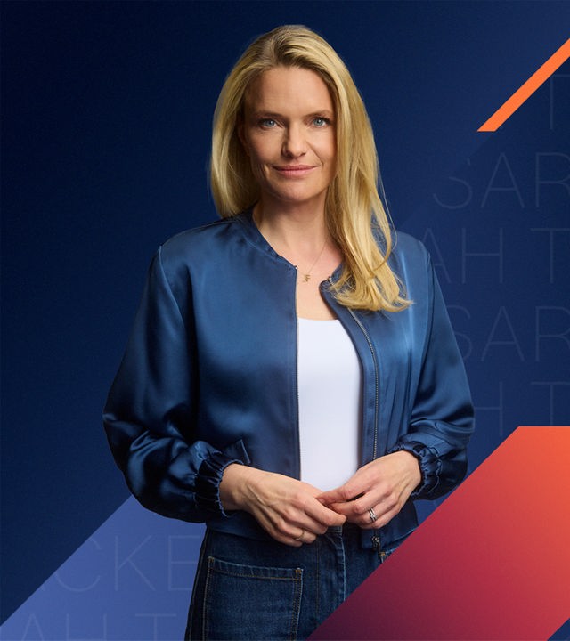 Sarah Tacke schaut selbstbewusst in die Kamera. Hinter ihr ist ein grafischer Hintergrund in blauen Farbklima mit orangenen und magentanen Akzenten zu sehen