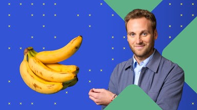 Dr. Leon Windscheid steht vor einem blauen Hintergrund und zeigt auf ein Bündel Bananen. Er lächelt leicht und blickt in die Kamera.