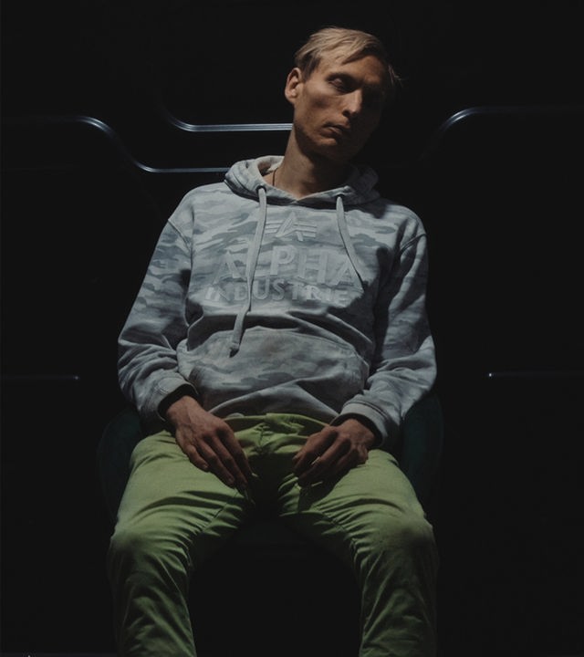 Timo sitzt im Laderaum eines Kleinbusses und schläft.