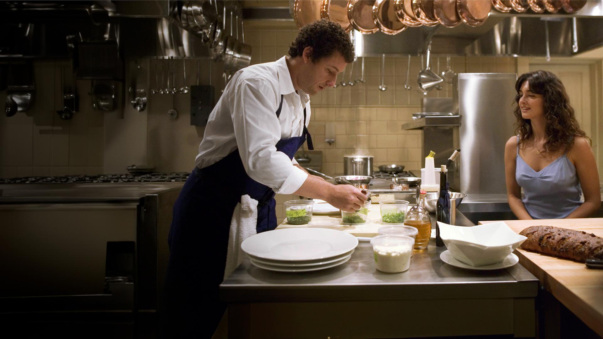 In einer professionellen Restaurantküche richtet John (Adam Sandler), ein Mann mit dunklen lockigen Haaren in weißer Kochjacke und dunkler Schürze, konzentriert mehrere kleine Schalen mit Kräutern oder Beilagen an. Ihm gegenüber sitzt Flor (Paz Vega), eine Frau mit langen dunklen Locken in einem hellblauen Kleid, und schaut ihn mit einem leichten Lächeln an. Über ihnen hängen zahlreiche glänzende Kupfertöpfe, auf der Arbeitsfläche liegen Teller, Schüsseln und ein Laib Brot.