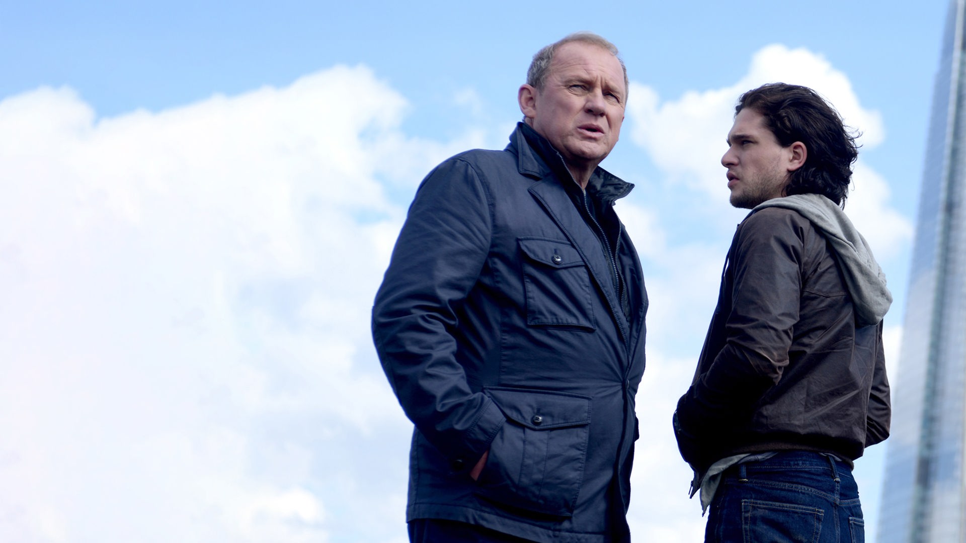 Vor der Hochhauskulisse von London stehen sich Harry (Peter Firth) und Will (Kit Harington) gegenüber.