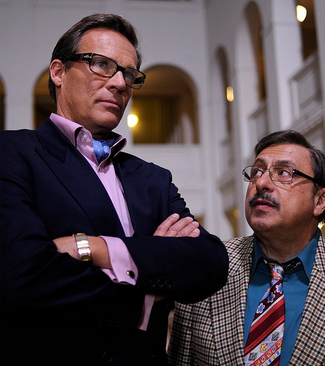 Werner Stankowski (Wolfgang Stumph) steht mit Rene Vonderecken (Christian Tramitz) in der Empfangshalle der Treuhand und schaut skeptisch zu ihm auf. Vonderecken steht mit verschränken Armen neben ihm und schaut in die Ferne.