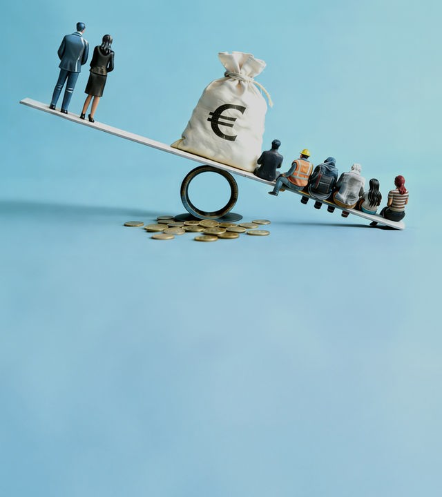 Wippe mit Figuren an beiden Enden. In der Mitte steht ein Sack mit einem Eurozeichen drauf.