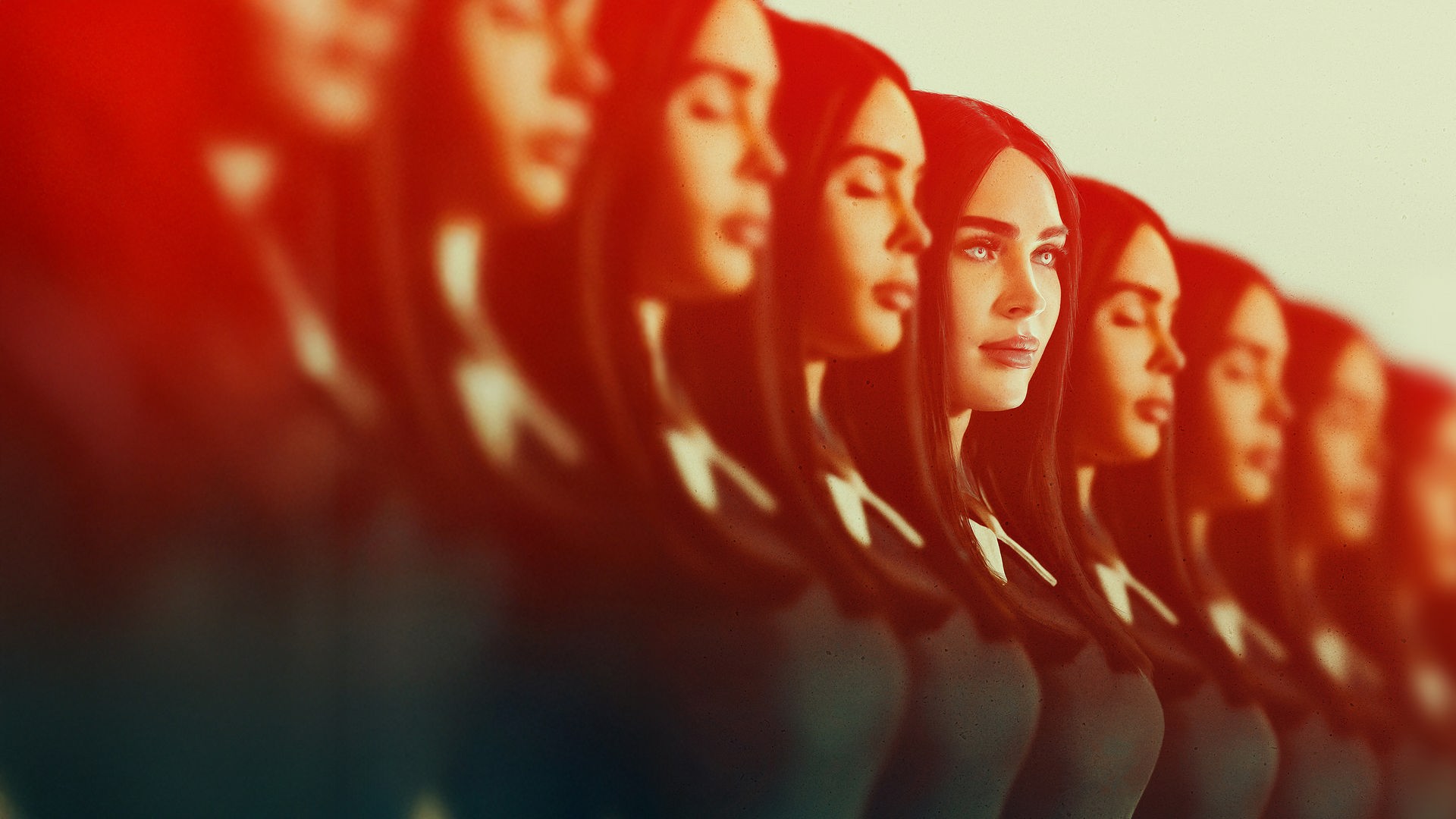 "Subservience": Plakatmotiv, Halbnahe: Mehrere Klone von Alice (Megan Fox), die rot ausgeleuchtet sind, stehen mit geschlossenen Augen in einer Reihe, doch eine der Personen blickt mit einem diabolischen Gesichtsausdruck und unnatürlich leuchtenden Augen nach vorne.