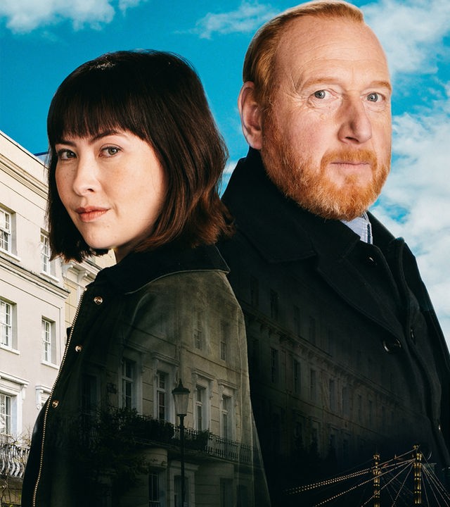 "The Chelsea Detective" zeigt DI Max Arnold (Adrian Scarborough) und DS Layla Walsh (Vanessa Emme) im Profil, wie sie ernst vor einem hellblauen Himmel stehen. In ihre dunkle Kleidung sind halbtransparente Ansichten von klassischen Londoner Stadthäusern eingeblendet.