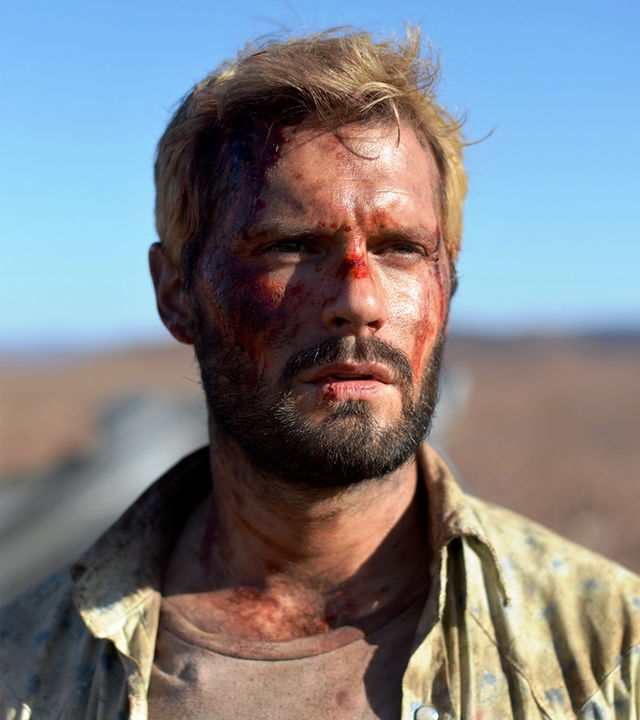 "The Last Journey - Die letzte Reise der Menschheit": Nahaufnahme: Paul (Hugo Becker) steht mit Schmutz und Schürfungen im Gesicht in der Sonne auf einer Schnellstraße in der Wüste.