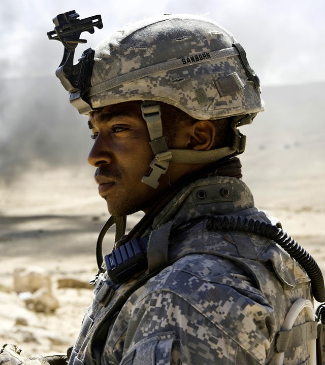 Sergeant JT Sanborn (Anthony Mackie) schaut nach links aus dem Bild heraus. Im Hintergrund ist eine karge Wüstenlandschaft mit einer Rauchsäule zwischen den Hügeln zu sehen