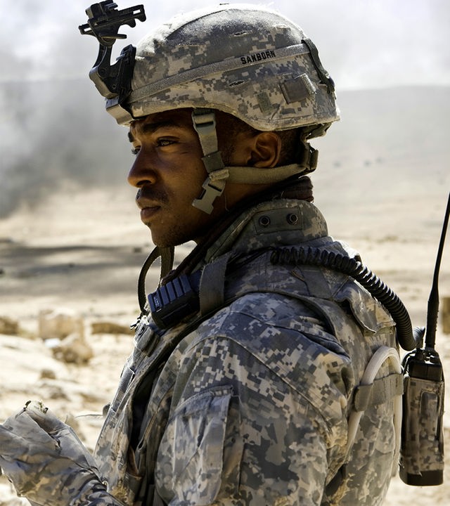 Sergeant JT Sanborn (Anthony Mackie) schaut nach links aus dem Bild heraus. Im Hintergrund ist eine karge Wüstenlandschaft mit einer Rauchsäule zwischen den Hügeln zu sehen