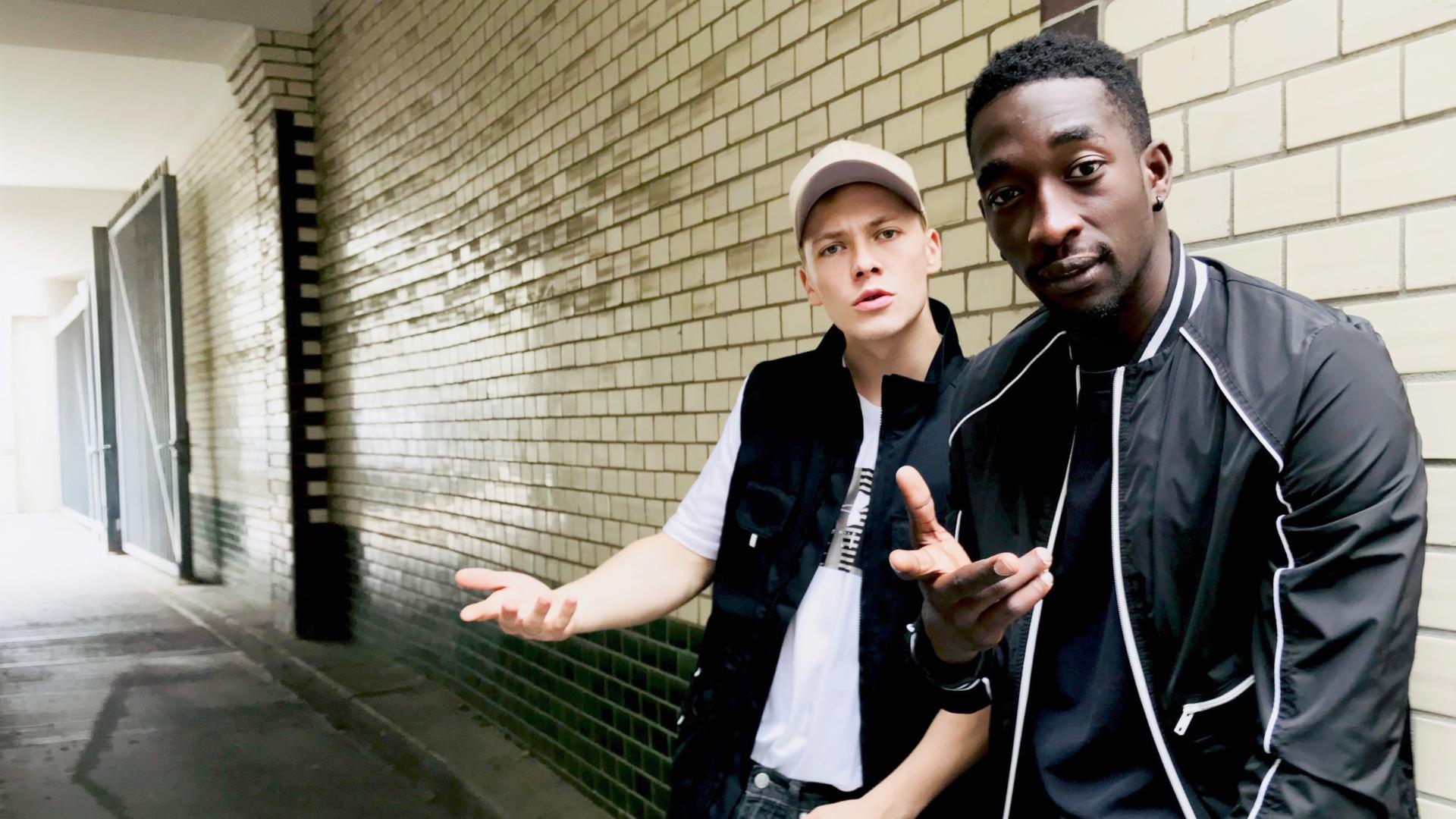Dennis (Julius Nitschkoff, l.) und Babtou (Farba Dieng, r.) sind beste Freunde. "Toubab": Dennis (Julius Nitschkoff) und Babtu (Farba Dieng) lehnen an einer gekachelten Wand. 