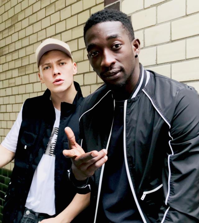 Dennis (Julius Nitschkoff, l.) und Babtou (Farba Dieng, r.) sind beste Freunde. "Toubab": Dennis (Julius Nitschkoff) und Babtu (Farba Dieng) lehnen an einer gekachelten Wand. 