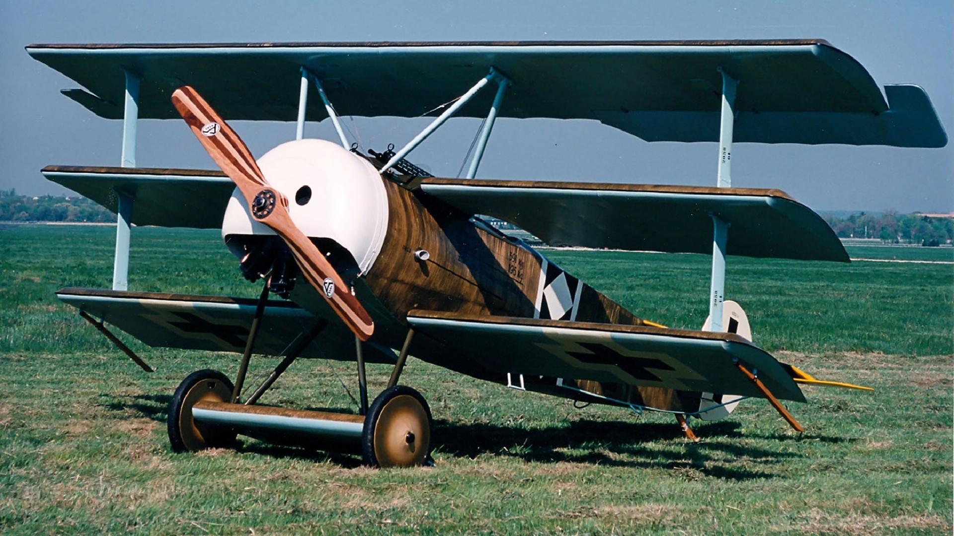 Ein Dreidecker des Types "Fokker Dr.I" steht auf einer Graswiese.