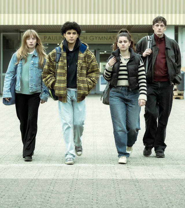 Julia (Mina-Giselle Rüffer), Waldi (Lukas von Horbatschewsky), Mina (Derya Akyol) und Tom (Kosmas Schmidt) entfernen sich vom Schuleingang und laufen zusammen über das Schulgelände in Richtung Kamera.