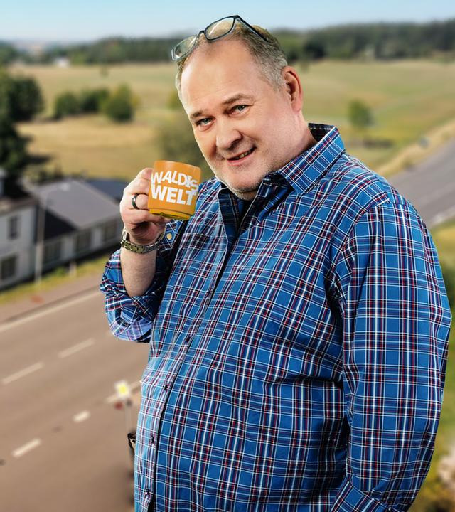 Walter Lehnertz mit einem Kaffeebecher in der Hand, auf dem "Waldis Welt" zu lesen ist.