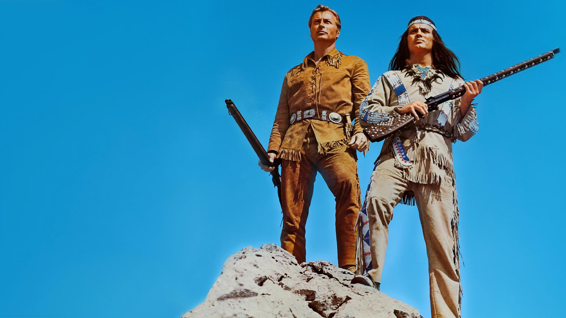 Old Shatterhand (Lex Barker) und Winnetou (Pierre Brice) stehen auf einer Felsspitze und blicken in die Ferne.
