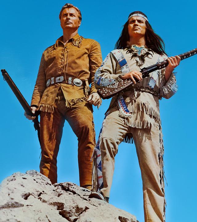 Old Shatterhand (Lex Barker) und Winnetou (Pierre Brice) stehen auf einer Felsspitze und blicken in die Ferne.