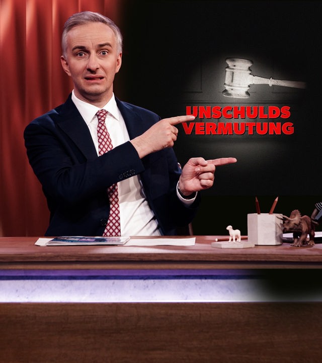 Jan Böhmermann sitzt am Schreibtisch.