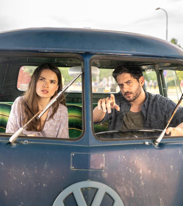 "Inga Lindström: Herz über Kopf": Nora (Zoe Moore) und Samu (Félix Herzog) sitzen auf den Vordersitzen eines alten VW-Busses und beobachten etwas in der Ferne.