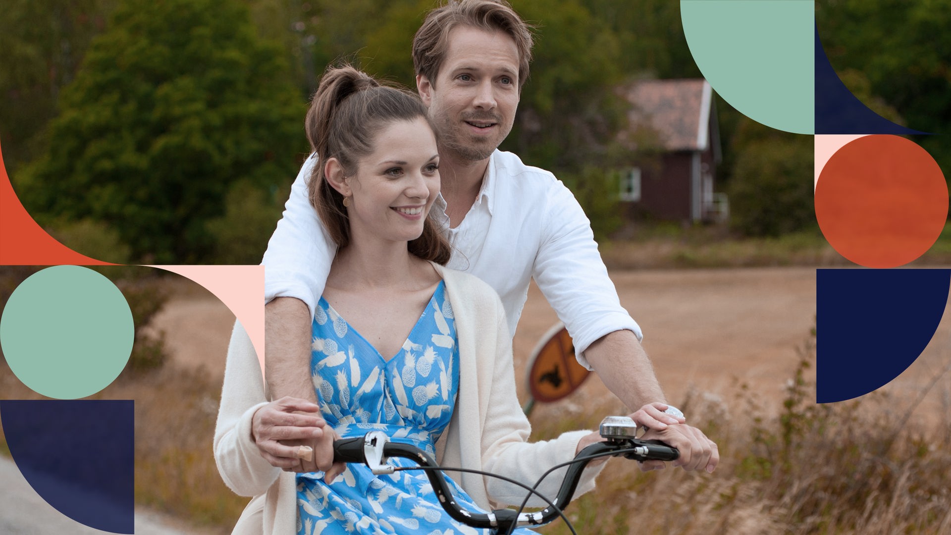 Robert (Christian Wunderlich) fährt Fahrrad, und Helen (Nathalie Thiede) sitzt auf der Querstange, beide halten sich am Lenker fest.