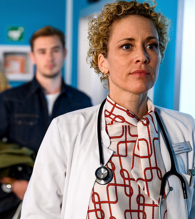 Rike (Isabell Horn), Betty (Annina Hellenthal) und Lukas (Niklas Löffler) stehen auf dem Krankenhausflur und schauen Dr. Helena von Arnstett (Claudia Hiersche) hinterher.