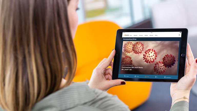 Frau hält ein Tablet mit der geöffneten, neuen ZDFheute-App