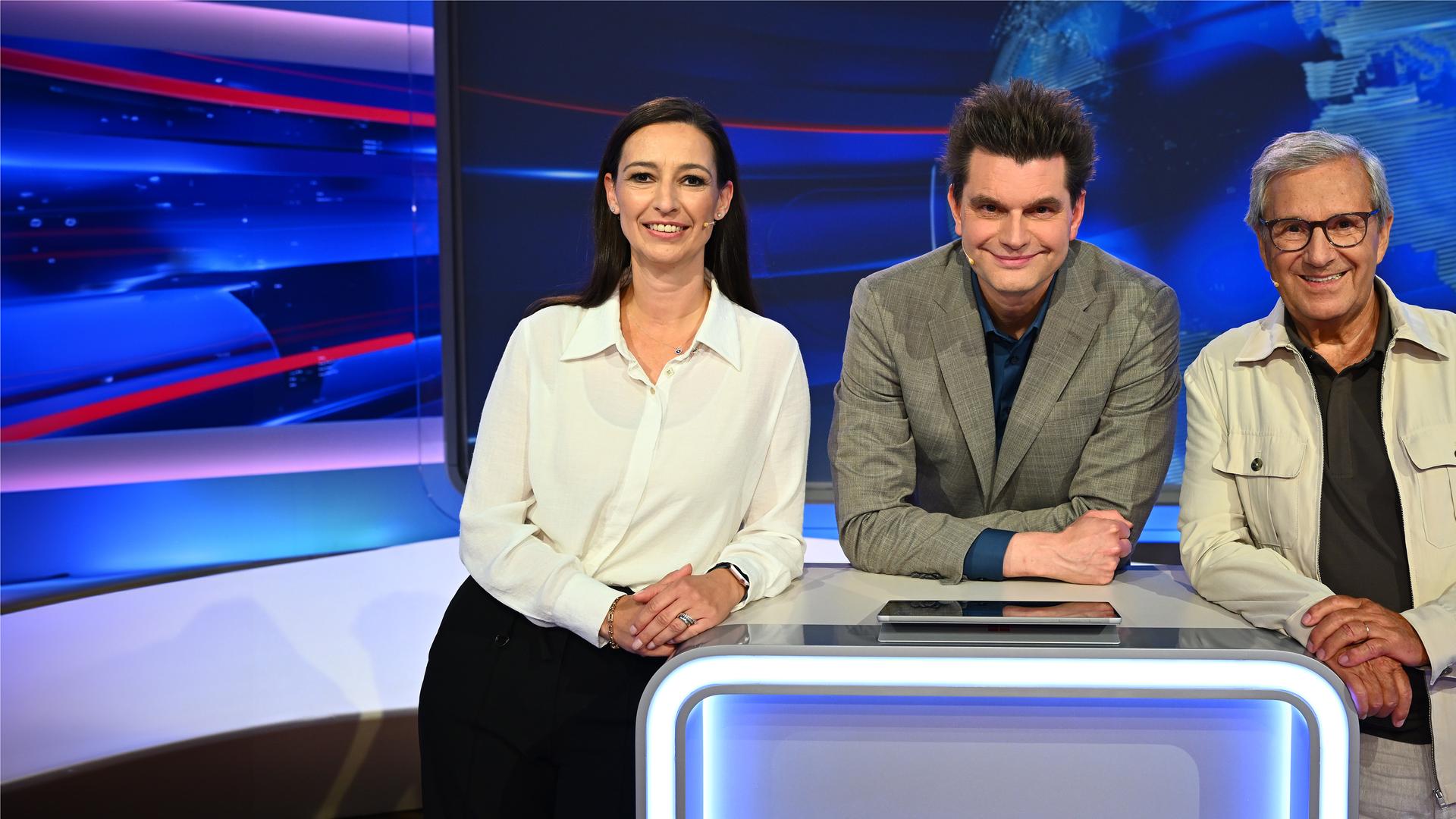 Lutz van der Horst steht im Studio hinter einem Pult. Links von ihm befindet sich Pinar Atalay und rechts von ihm Jan Hofer.