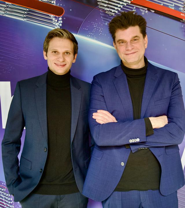 Fabian Köster (l.) und Lutz van der Horst (r.) posieren vor dem "heute-show"-Logo. Sie tragen beide einen Anzug.