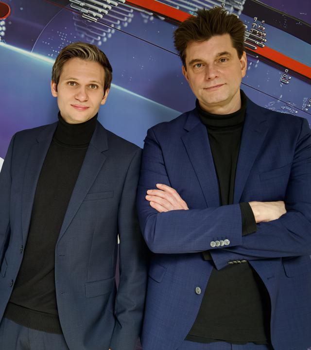 Fabian Köster (l.) und Lutz van der Horst (r.) posieren vor dem "heute-show"-Logo. Sie tragen beide einen Anzug.