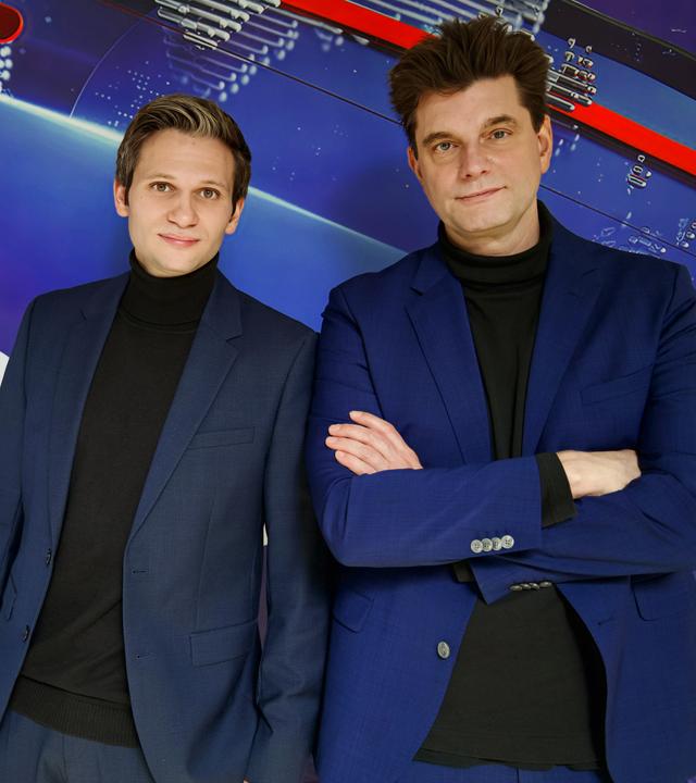 Fabian Köster (l.) und Lutz van der Horst (r.) posieren vor dem "heute-show"-Logo. Sie tragen beide einen Anzug.