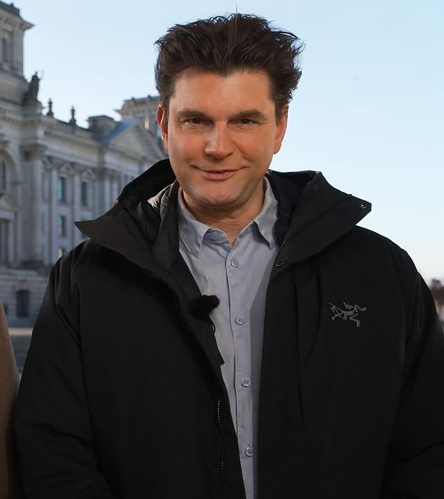 Die Medienjournalisten des Jahres 2025 im Bereich Unterhaltung, Fabian Köster (l.) und Lutz van der Horst (r.), stehen vor dem Reichstagsgebäude in Berlin und schauen in die Kamera.