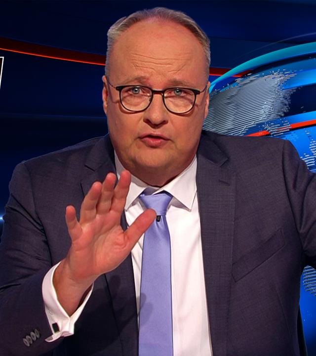 Oliver Welke sitzt am Schreibtisch. Links neben ihm ist ein Bild von Dieter Bohlen zu sehen, der eine vegetarische Wurst hält. Unter dem Bild steht: Mann, ist das ein Veggie-Pimmel!