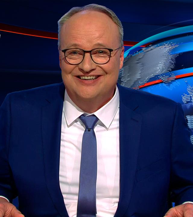 Oliver Welke sitzt am Schreibtisch. Links neben ihm steht: "Hurra, es ist eine kleine GroKo".