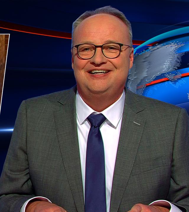 Oliver Welke sitzt am Schreibtisch. Links im Bild ist eine Fotomontage von Donald Trump mit verschränkten Armen im Weihnachtsmannkostüm vor einer festlich geschmückten Haustür zu sehen. Unten im Bild befindet sich ein rotes Geschenkpaket mit grüner Schleife und der Schriftzug "Wir geben nix".