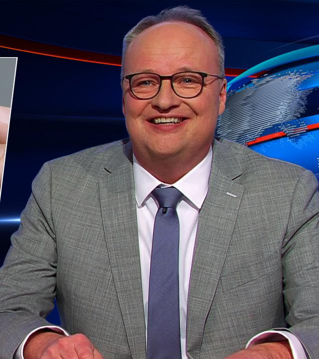 Oliver Welke sitzt am Schreibtisch. Links von ihm ist eine Fotomontage von Friedrich Merz zu sehen, der einen Glückskeks öffnet. Darin befindet sich ein Zettel mit dem Spruch: "Ohne China sind wir am Arsch".