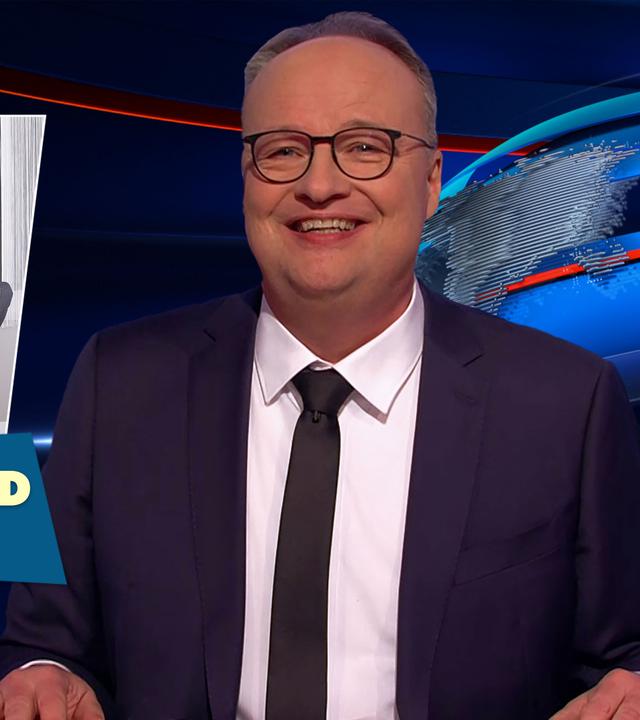 Oliver Welke sitzt am Schreibtisch. Links im Bild ist eine Fotomontage von Wladimir Putin und Donald Trump in einem Büro zu sehen. Putin sitzt mit auf dem Tisch ausgestreckten Beinen an einem Schreibtisch, während Trump im Outfit einer Sekretärin etwas notiert. Darunter steht: Frollein Donald zum Diktat.