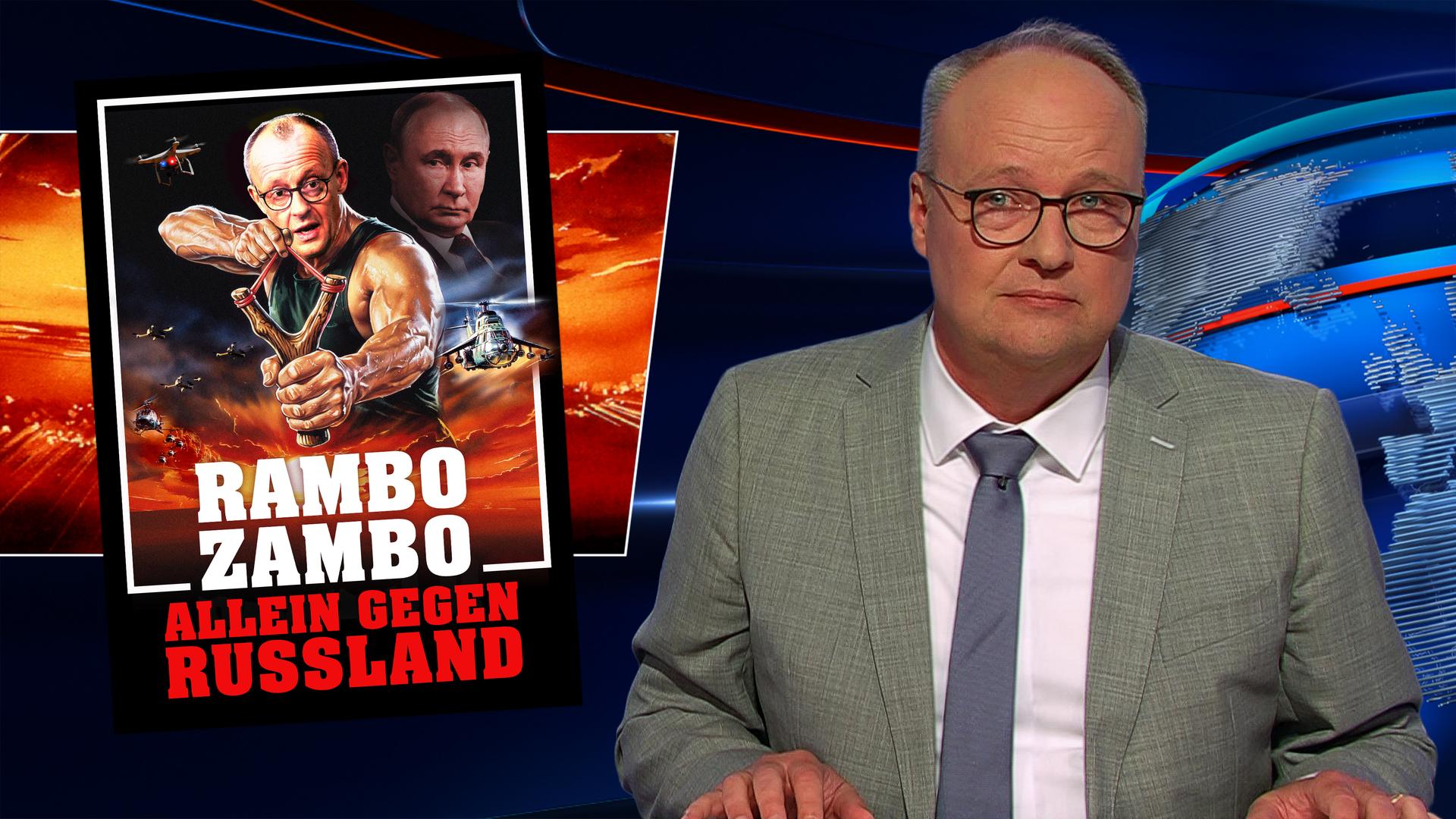 Oliver Welke sitzt rechts im Bild. Links im Bild ist eine satirische Fotomontage im Actionfilm-Stil zu sehen, auf der Friedrich Merz als Actionheld mit einer gespannten Schleuder dargestellt ist. Im Hintergrund befindet sich Wladimir Putin. Am unteren Bildrand steht "Rambo Zambo – Allein gegen Russland".