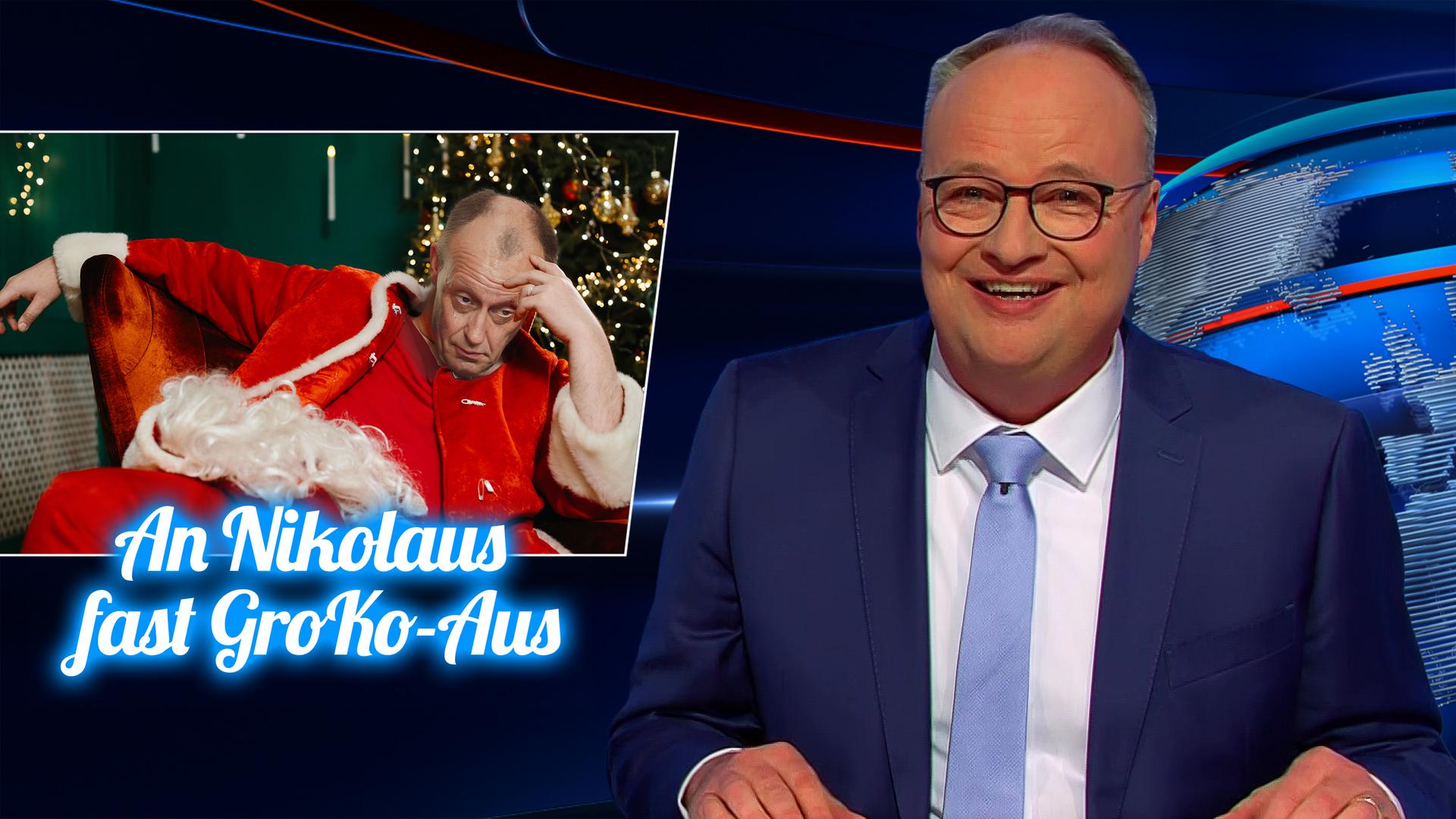 Oliver Welke sitzt am Schreibtisch. Links von ihm ist eine Fotomontage von Friedrich Merz in einem Nikolauskostüm zu sehen, der in erschöpfter Haltung auf einem Stuhl sitzt. Unter dem Bild steht: An Nikolaus fast GroKo-Aus.