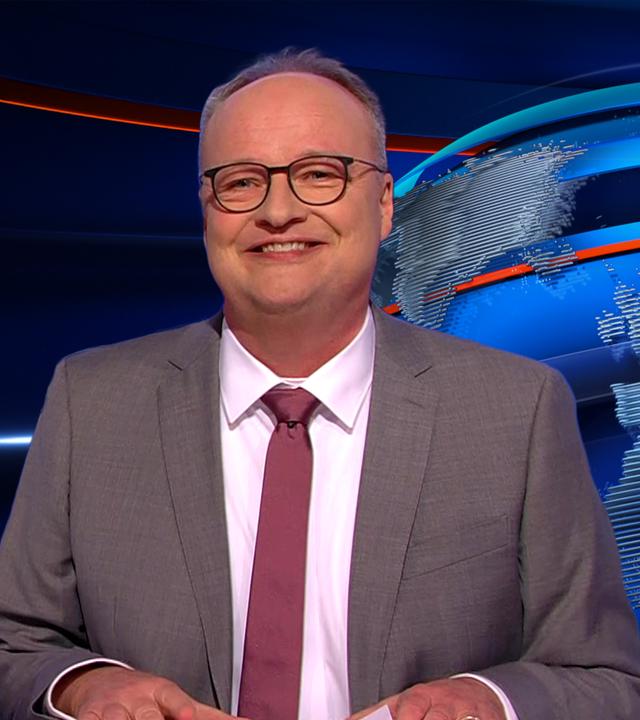 Oliver Welke sitzt am Schreibtisch. Links im Hintergrund ist eine satirische Fotomontage von Donald Trump in einem Fahrgeschäft "Freefall-Tower" zu sehen. Am unteren Bildrand steht: "Free Fall Trump Tower".