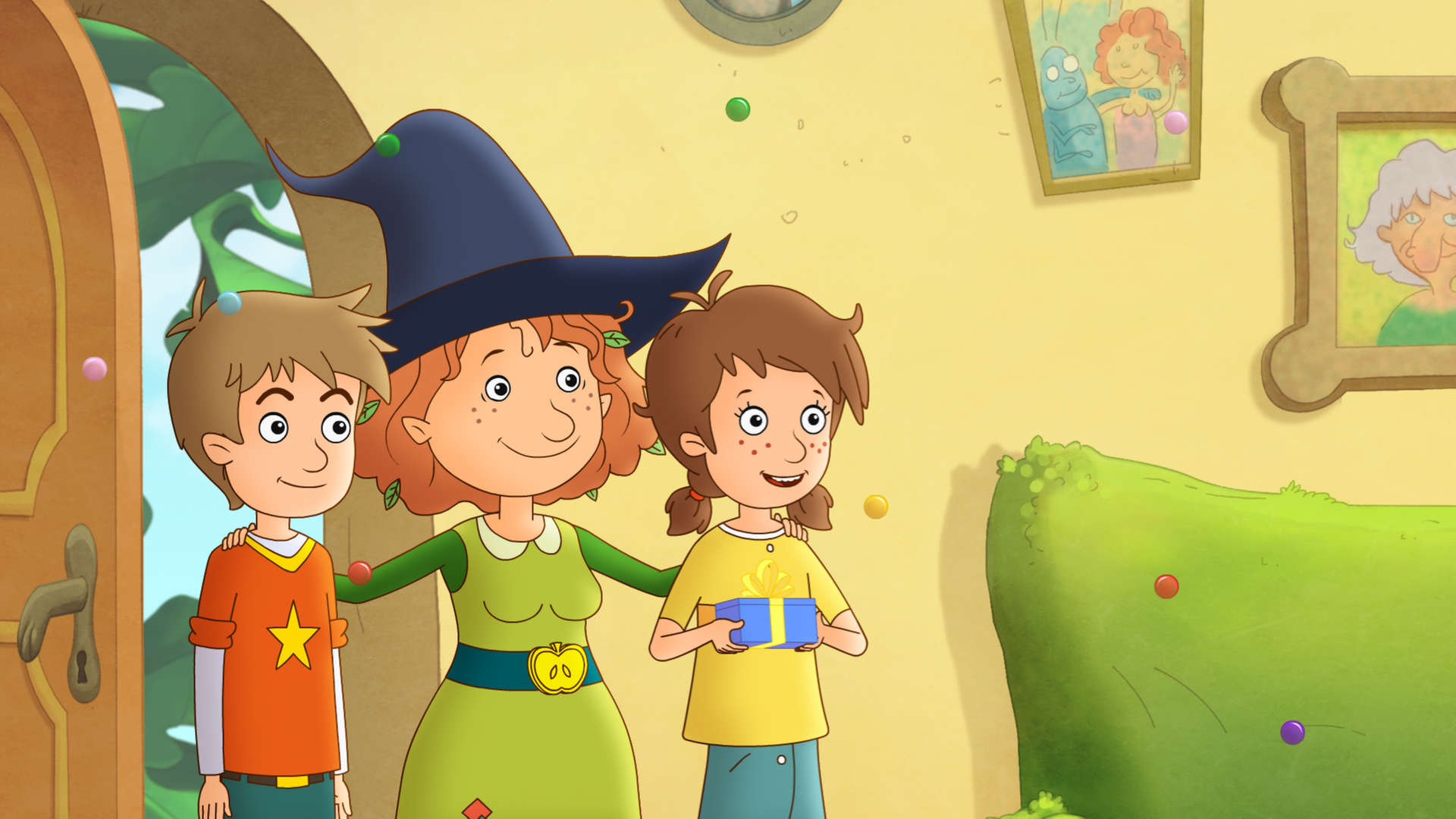 Petronella feiert in ihrer Wohnung mit Lea und Luis ihren Geburtstag. Lea hält ein Geschenk in den Händen.