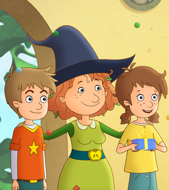 Petronella feiert in ihrer Wohnung mit Lea und Luis ihren Geburtstag. Lea hält ein Geschenk in den Händen.