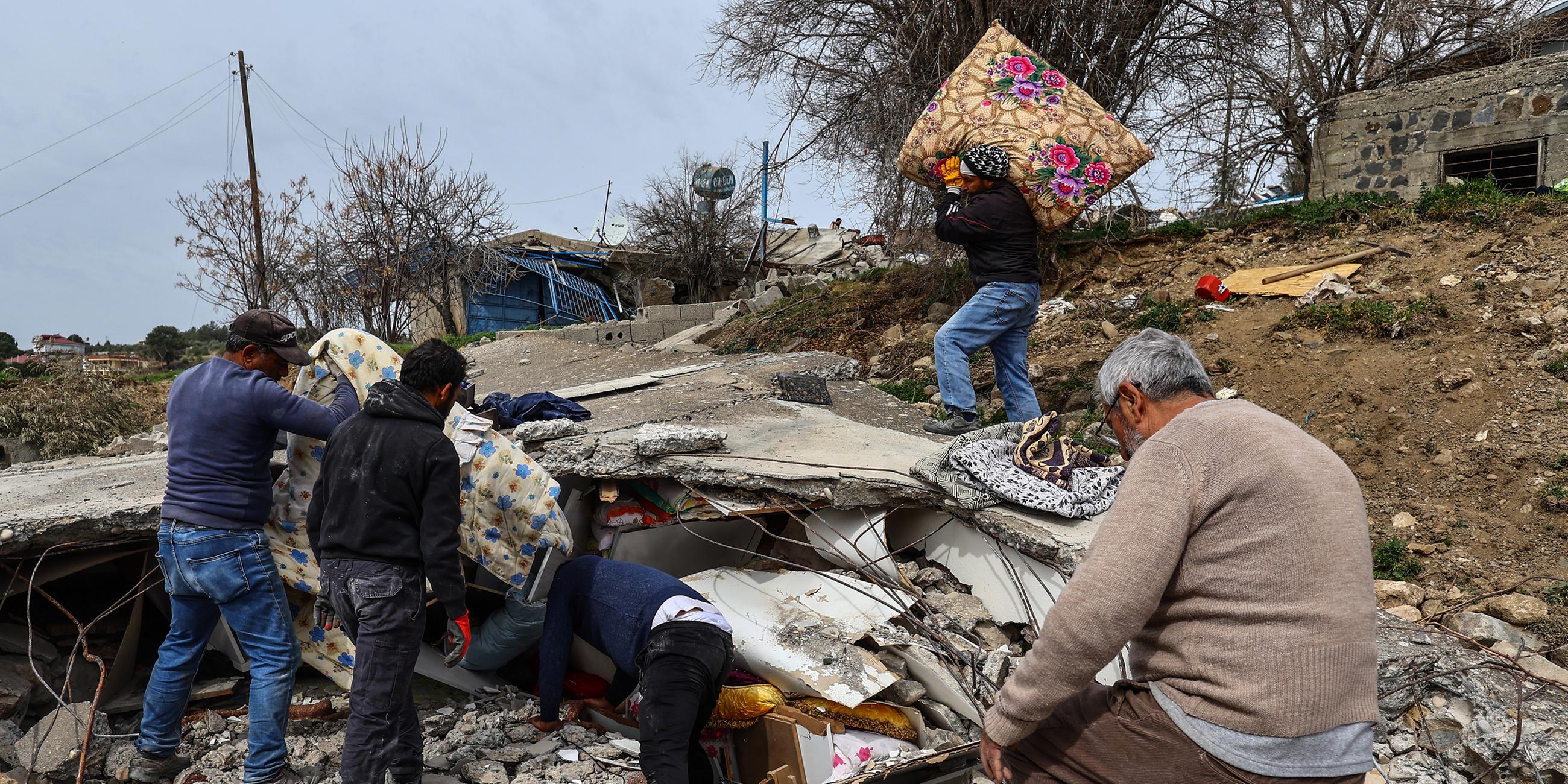 Menschen suchen nach Habseligkeiten in den Trümmern nach den schweren Erdbeben in der Südtürkei