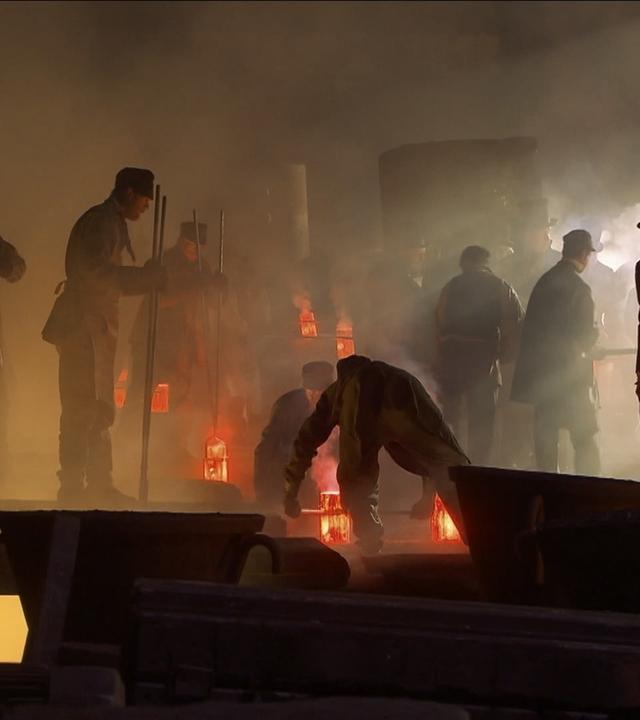 Spielszene: In einer historischen Stahlfabrik wird Gussstahl hergestellt.